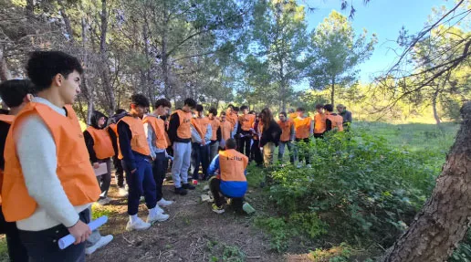 Grupo de jóvenes voluntarios con chalecos naranjas en una actividad medioambiental