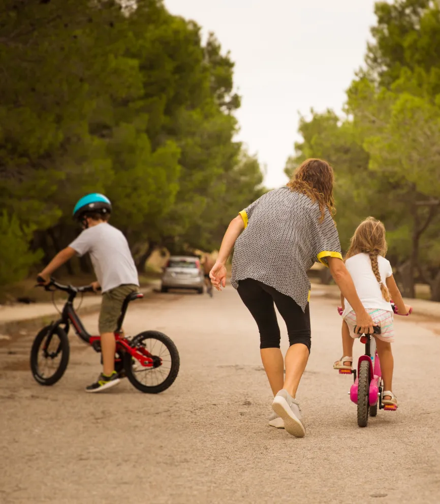 Niños en bicicleta y patinete paseando por un parque