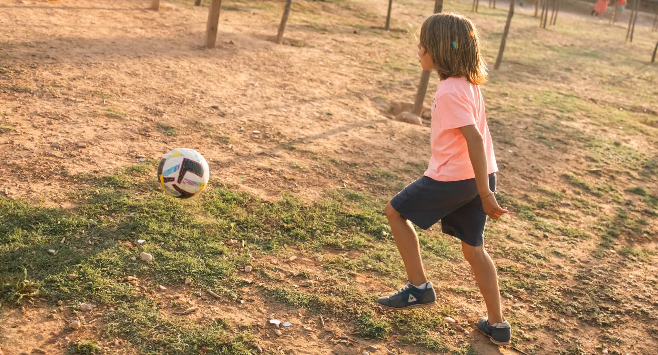 Niño jugando con un balón sobre el césped