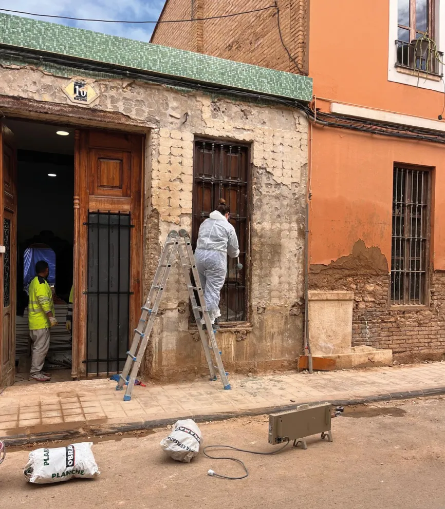 Operario rehabilitando la fachada de una vivienda afectada por la DANA