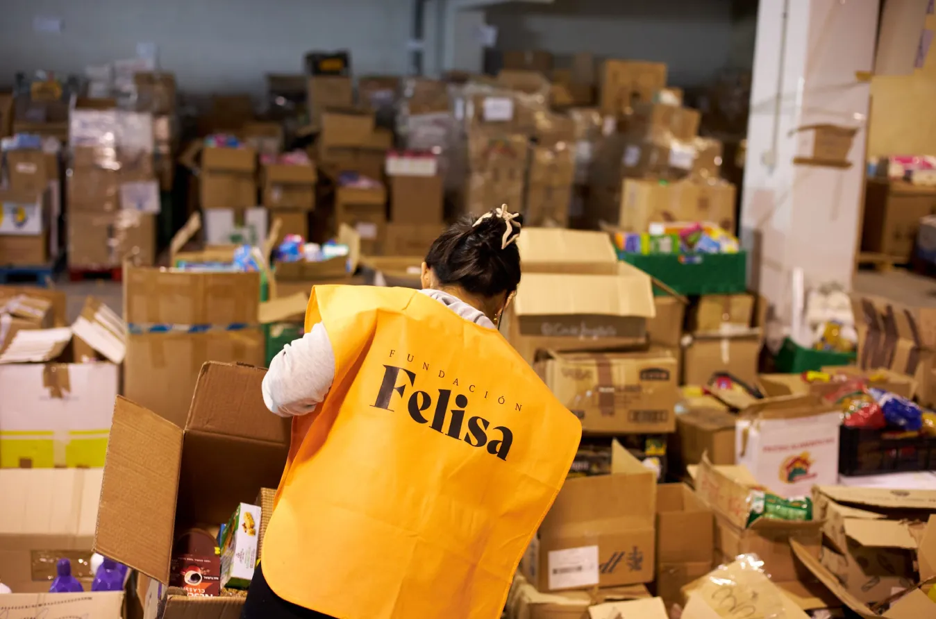 Voluntaria clasificando cajas de donaciones en una nave