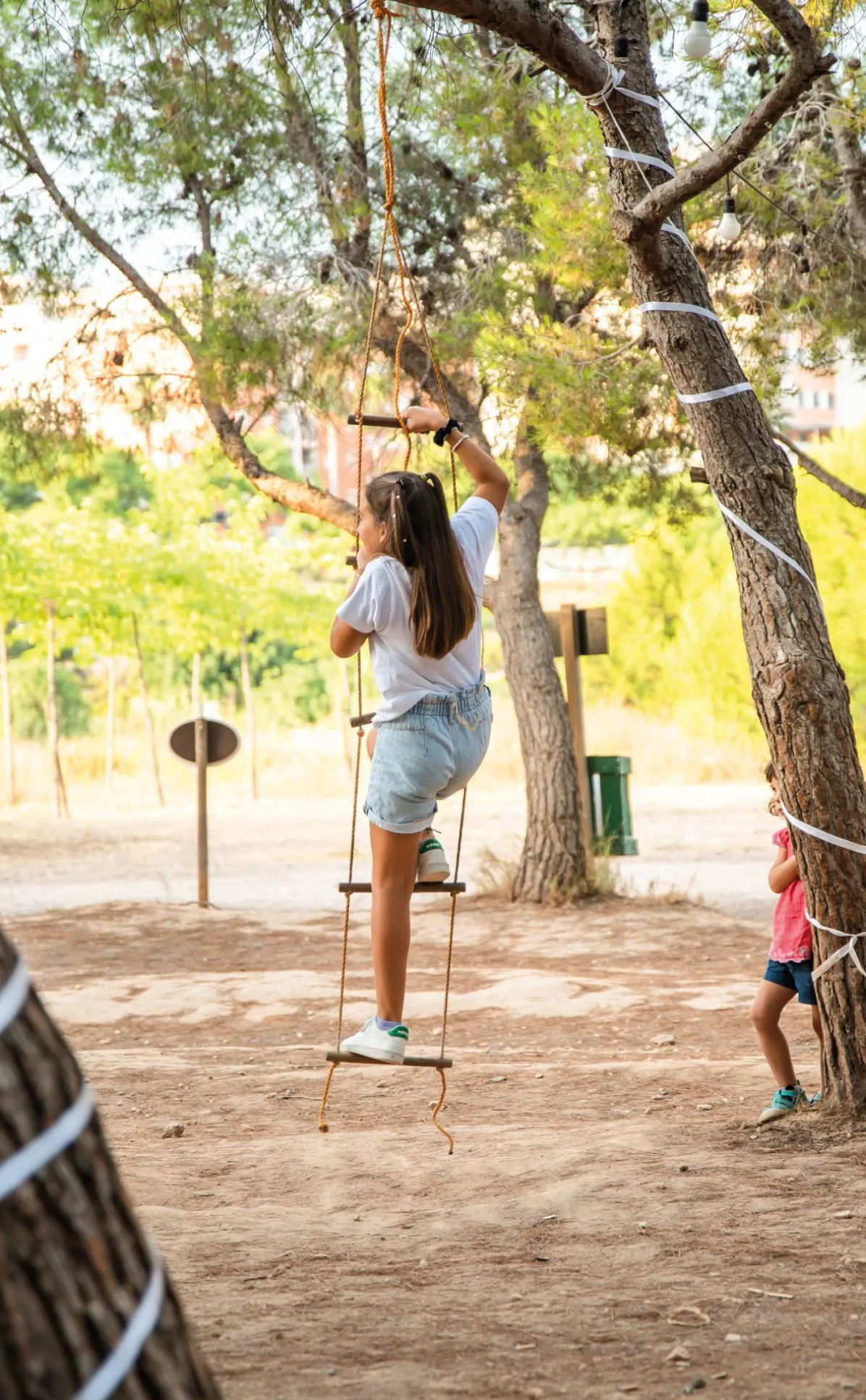 Joven subiendo por una escalera de cuerda entre los árboles de Parque Felisa