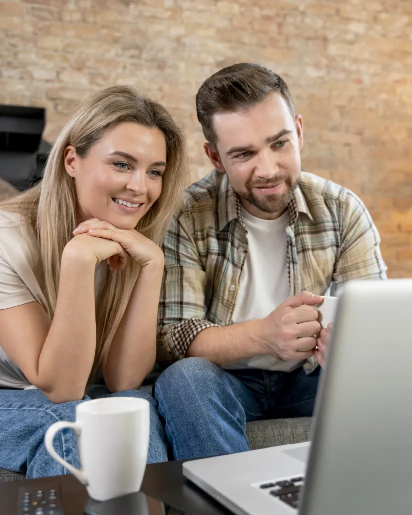 Pareja consultando un ordenador portátil desde su sofá